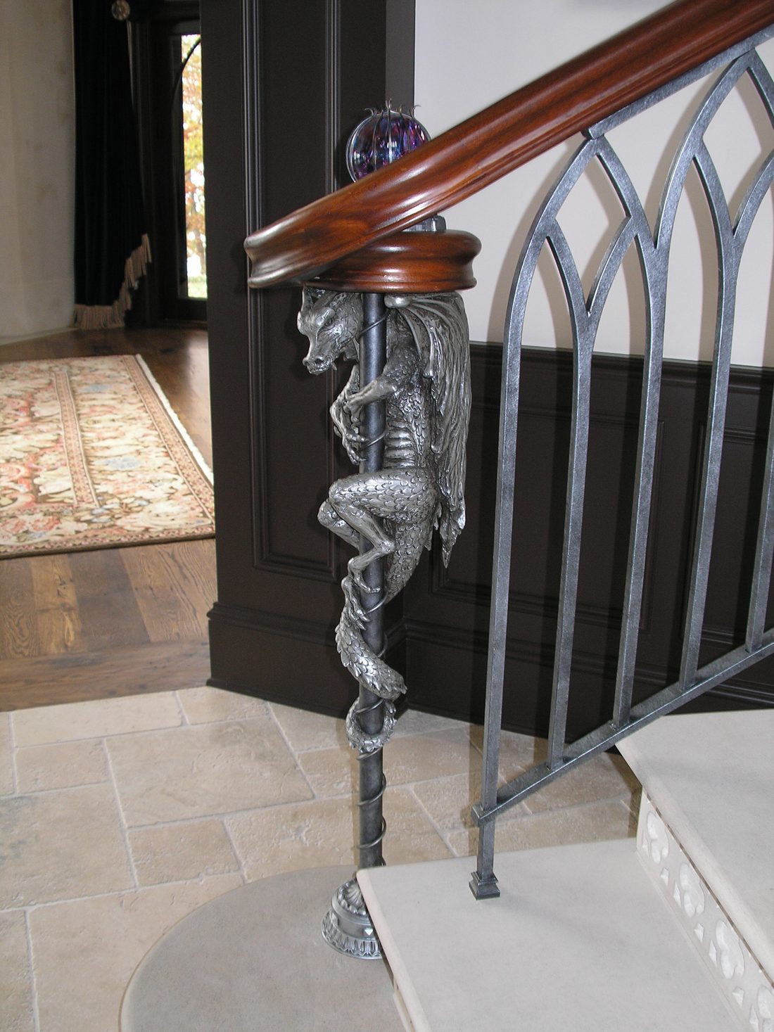 A cast-metal dragon coiled around the newel post of a French Gothic staircase.