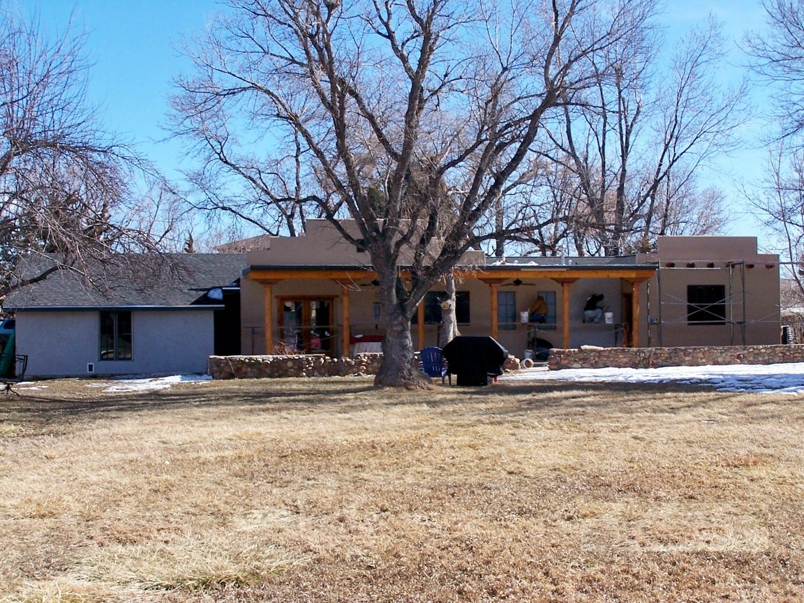The rear addition under construction — new framing and stucco extending the house toward the garden, scaffolding still in place.