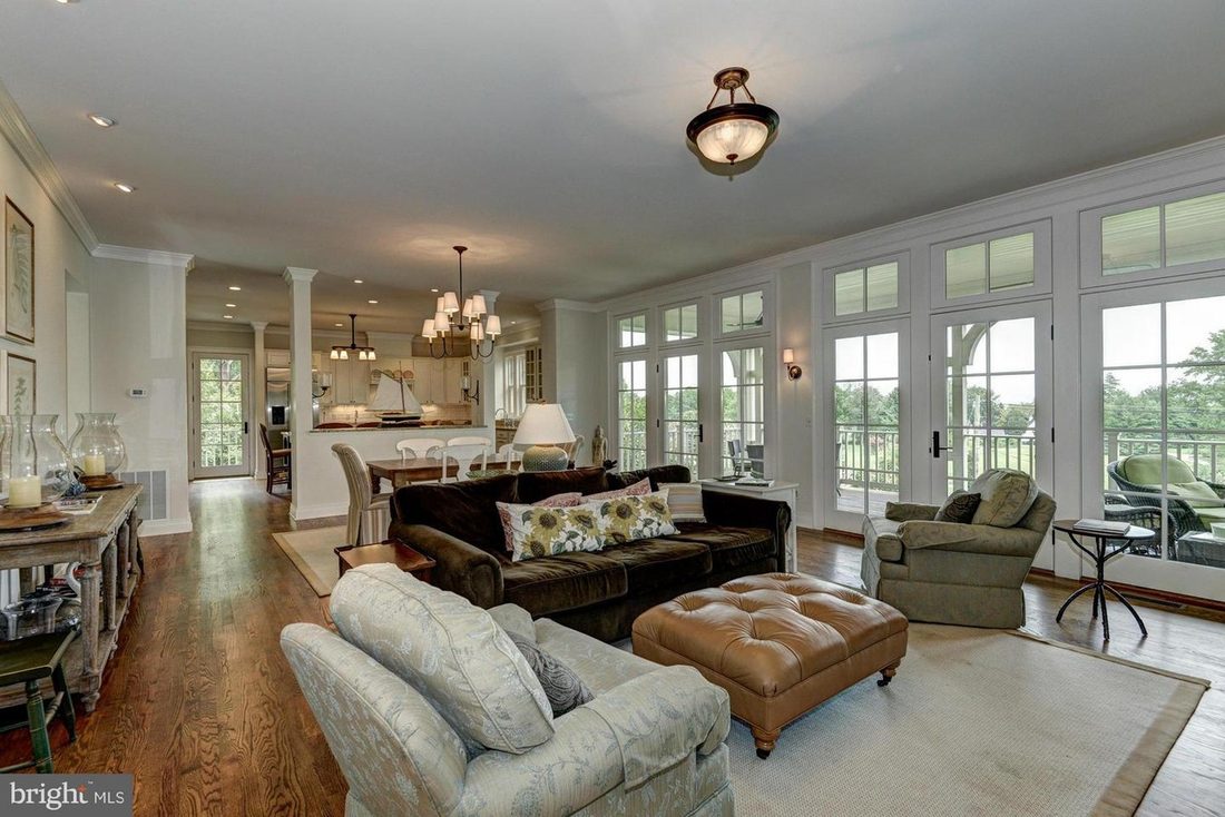 The open living room with hardwood floors, a wall of French doors and arched transoms framing the lawn beyond.